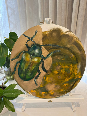 A canvas painting featuring a realistic green beetle on a circular canvas, with a background that blends into an abstract pattern of yellow and green hues.